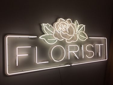 White neon lettering spells 'Florist' with floral design